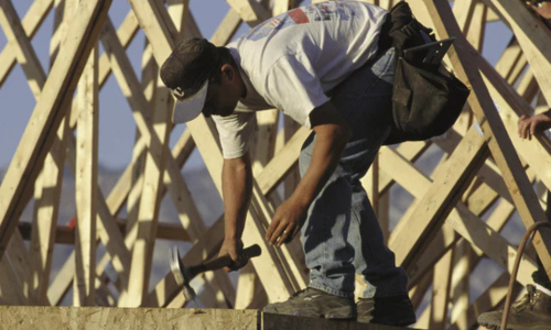 A contractor using a clam hammer while working on framing a building