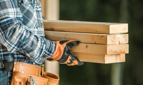 A contractor carrying lumber